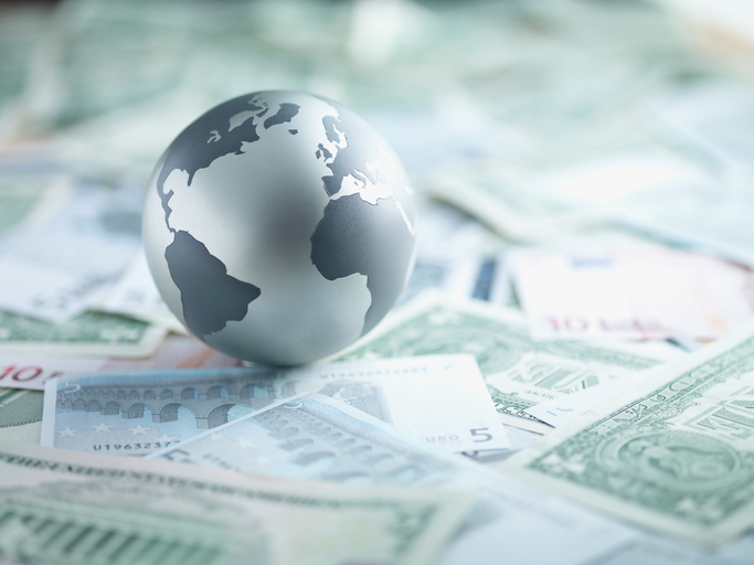 Composite image of a globe atop various currencies