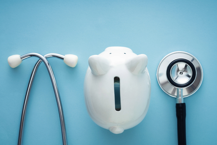 Photo of stethoscope and piggy bank.
